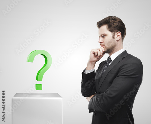 Plakat w ramie Young businessman look at the green question marks