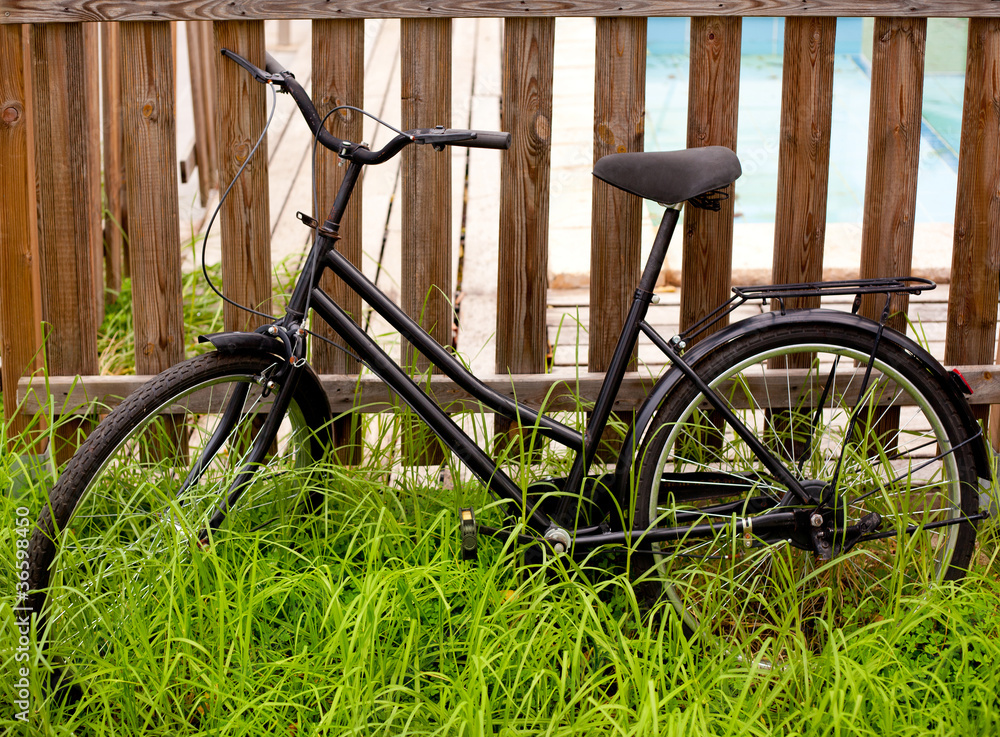 black grunge bicycle aged on a wood fence