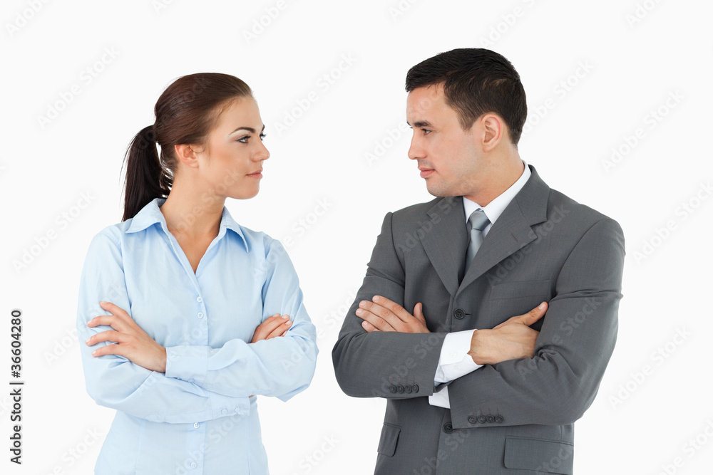 Serious business partners with arms folded looking at each other Serious business partners with arms folded looking at each other