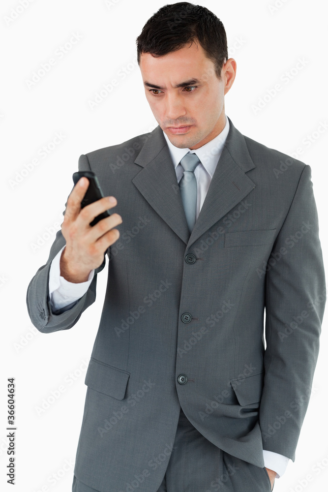 Serious looking businessman looking at his cellphone Serious looking businessman looking at his cellphone