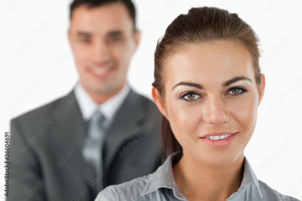 Close up of smiling businesswoman with colleague behind her Close up of smiling businesswoman with colleague behind her