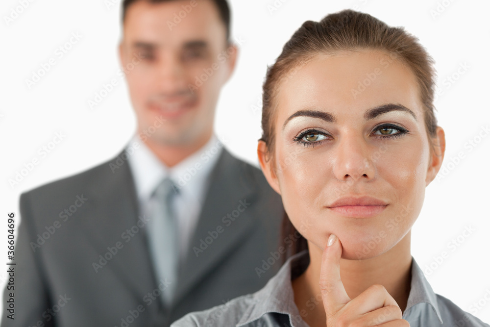 Close up of thoughtful businesswoman with colleague behind her Close up of thoughtful businesswoman with colleague behind her