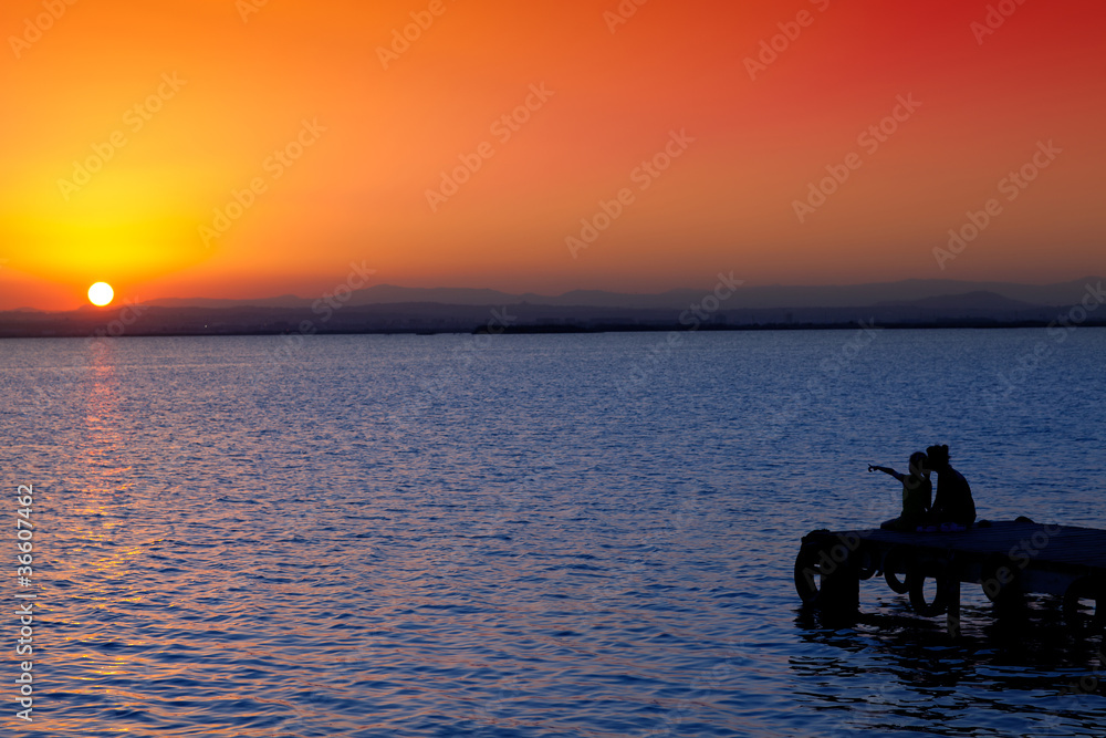 Mother and daughter in sunset jetty lake