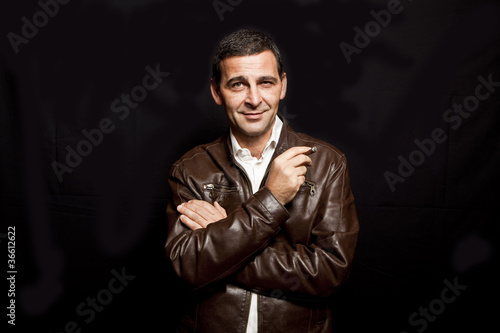 portrait of a cool mature man with leather jacket over black bac