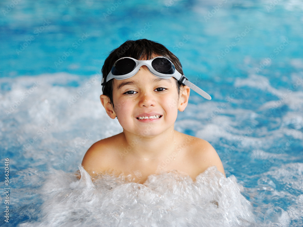 Little cute  boy in blue water of the swimming pool,