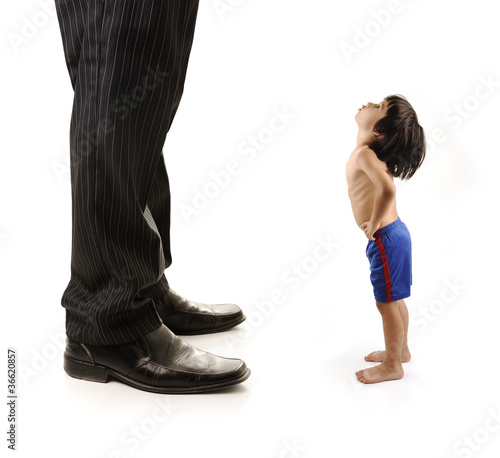 Little small child  is looking at the giant legs of  businessman photo