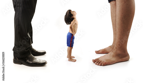 Little small child  is looking at the giant legs of two men photo