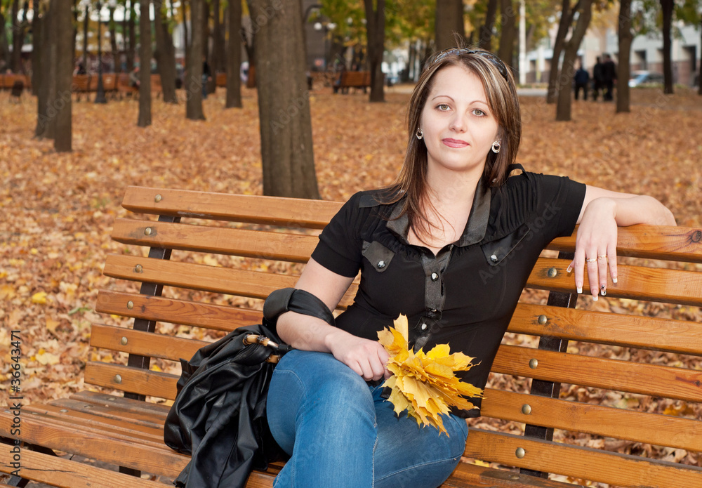 Beautiful girl sitting on a bench in autumn park Beautiful girl sitting on a bench in autumn park