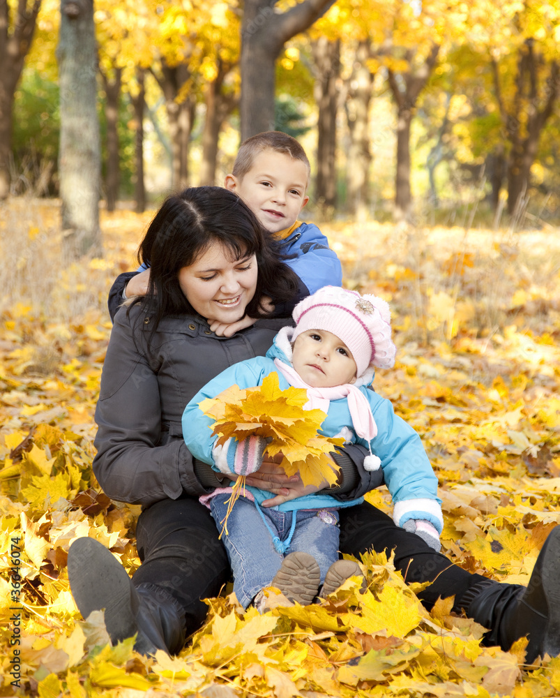 Mother and her childrens are playing in autumn park Mother and her childrens are playing in autumn park