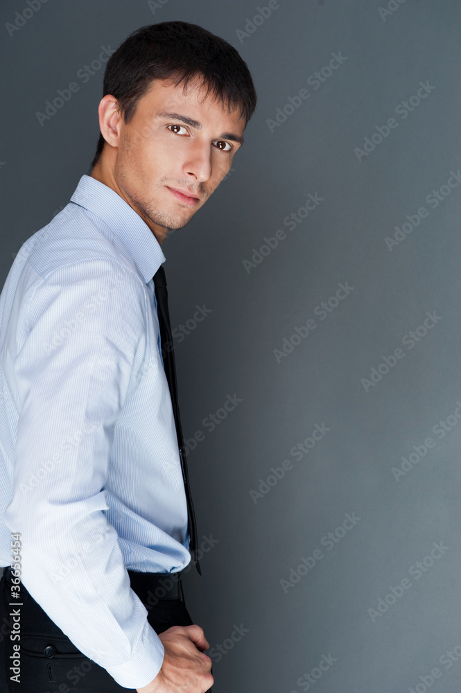 Closeup of a young smiling business man standing confidently aga Closeup of a young smiling business man standing confidently aga