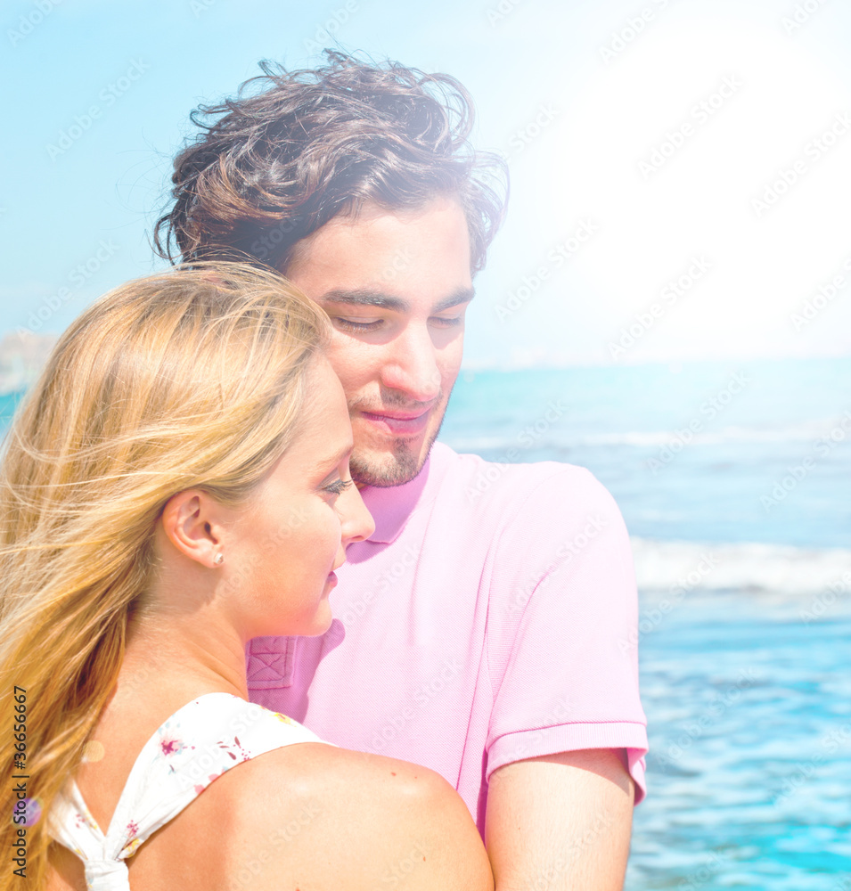 Portrait of young couple in love embracing at beach and enjoying Portrait of young couple in love embracing at beach and enjoying