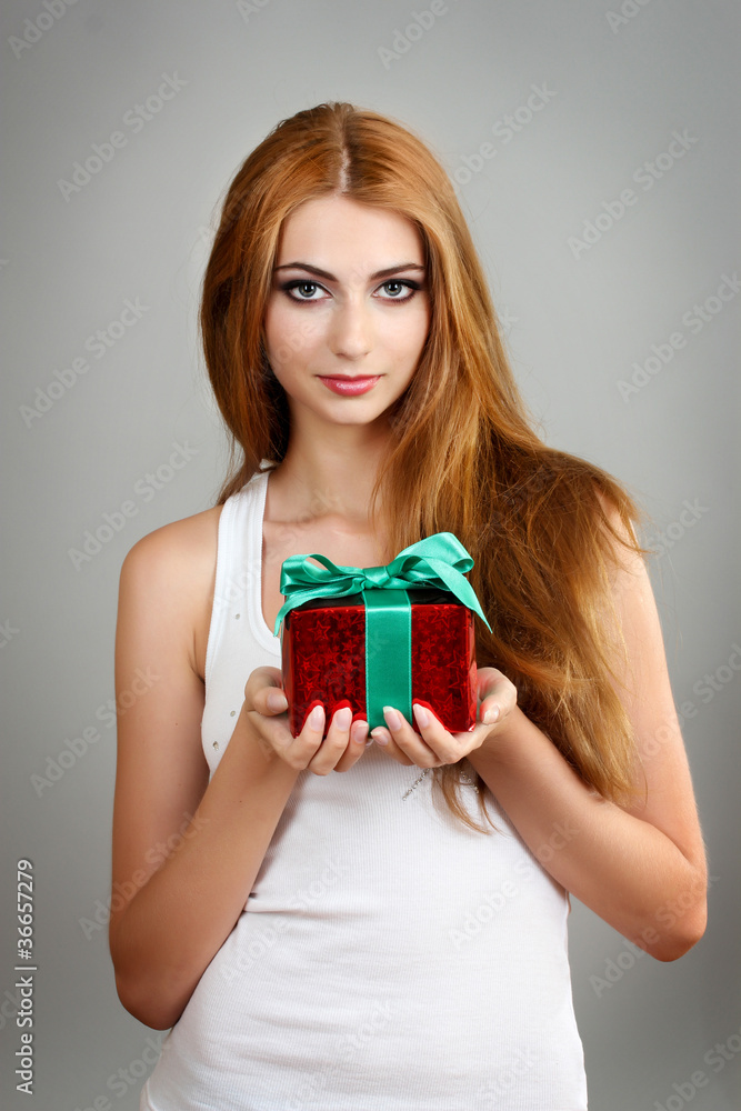Beautiful young girl with present box on gray background Beautiful young girl with present box on gray background