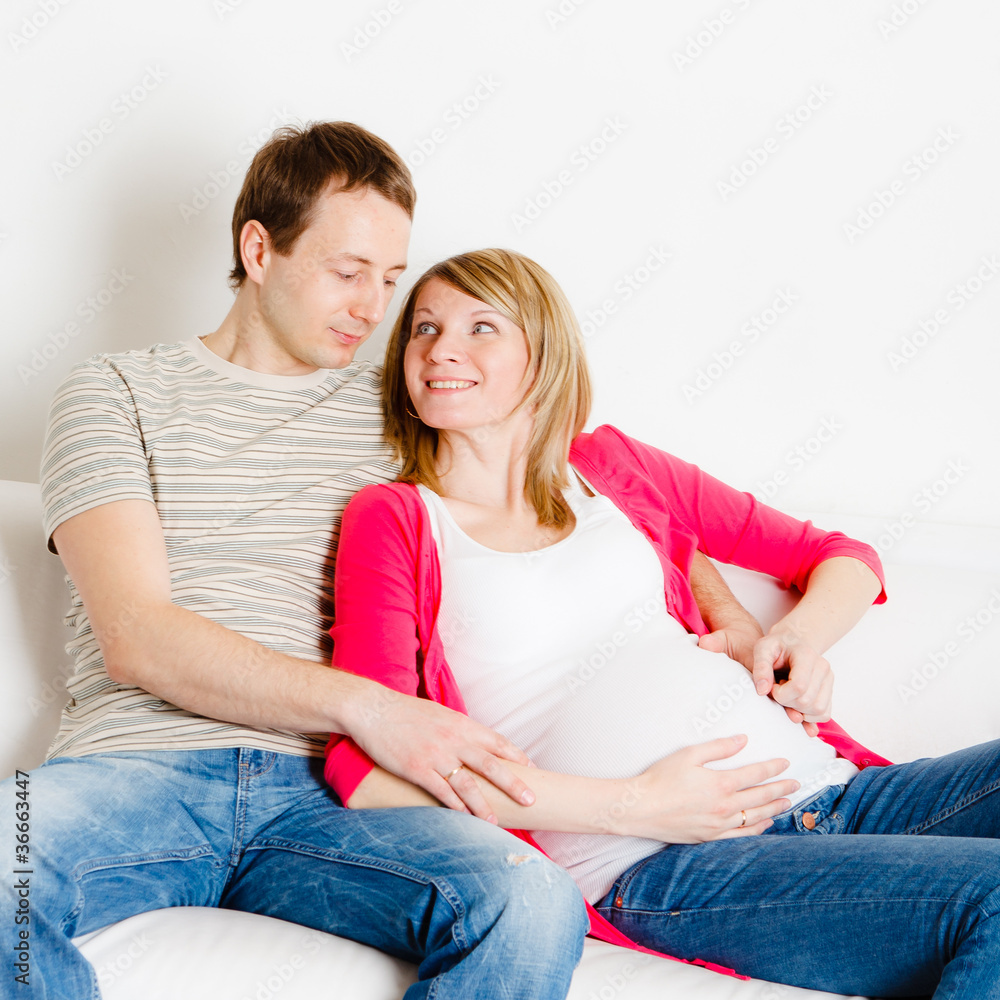 Pregnant woman with her husband sitting on sofa Pregnant woman with her husband sitting on sofa