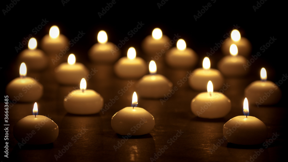 Group of burning candles at a black background with selective fo Group of burning candles at a black background with selective fo
