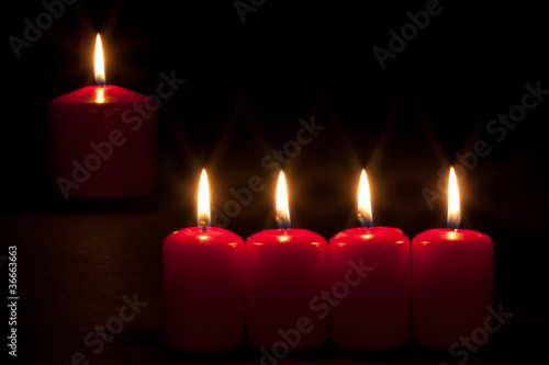 Set of red candles burning in the dark