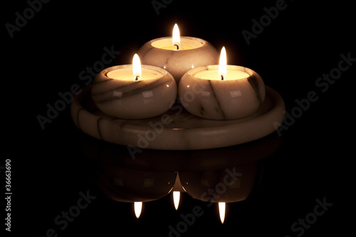 Decorative candlestick of marble with three lights at a black ba