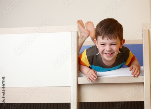 Little kid laughing on top of bunk bed