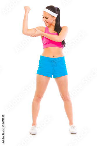 Full length portrait of fitness girl checkin checking muscles
