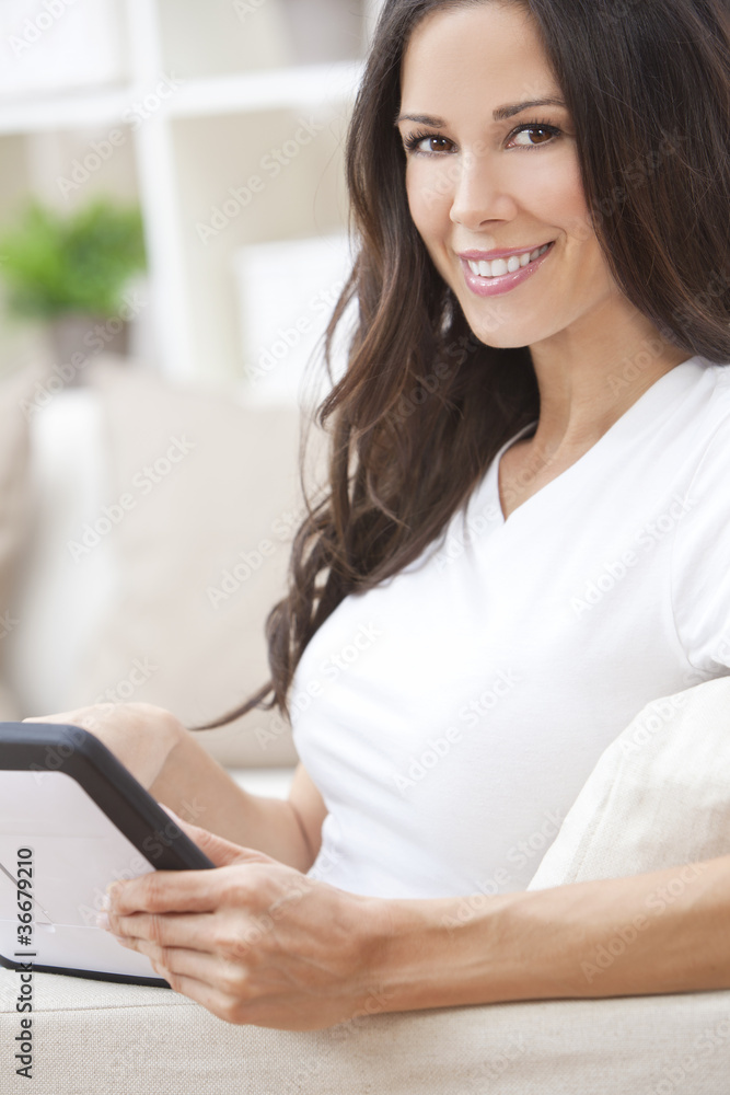 Young Brunette Woman Using Tablet Computer At Home on Sofa Young Brunette Woman Using Tablet Computer At Home on Sofa