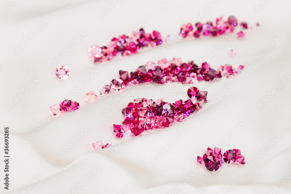 Diamond (ruby) stones heap over cream silk cloth background Diamond (ruby) stones heap over cream silk cloth background
