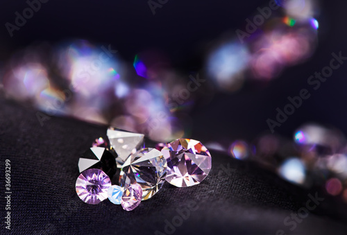Diamond (small purple jewel) stones heap over black silk cloth b photo
