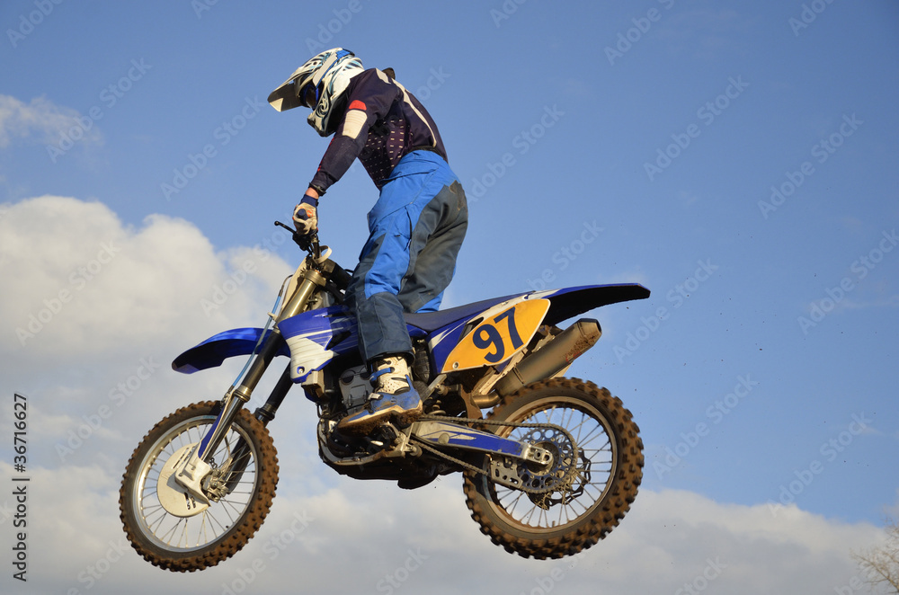Motocross rider on flying through the air against the sky Motocross rider on flying through the air against the sky
