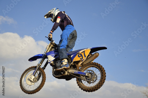 Fototapeta Naklejka Na Ścianę i Meble -  Motocross rider on flying through the air against the sky