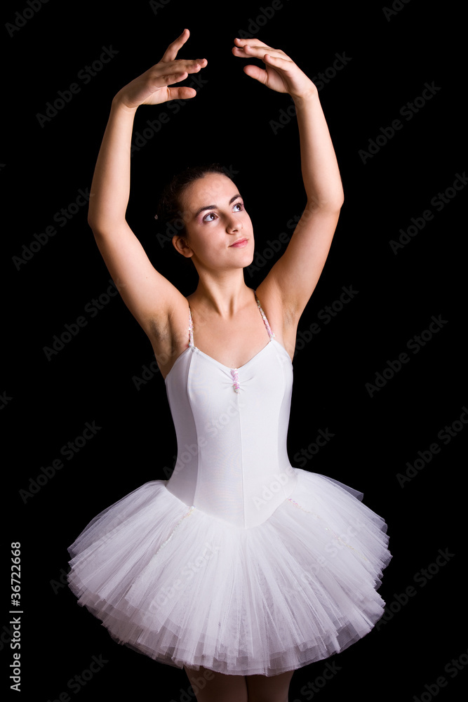 Fototapeta premium Teen girl ballet dancer standing in a tutu on a black background