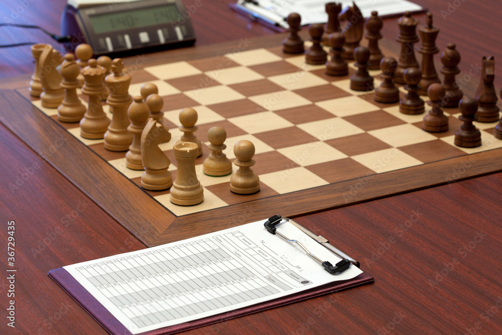 Wooden chess is placed on chessboard. Electronic clock. Wooden chess is placed on chessboard. Electronic clock.