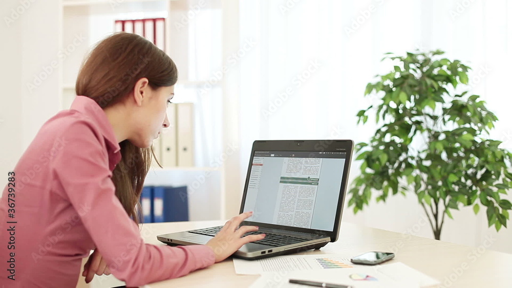 Business woman working on a computer turns at camera. Business woman working on a computer turns at camera.