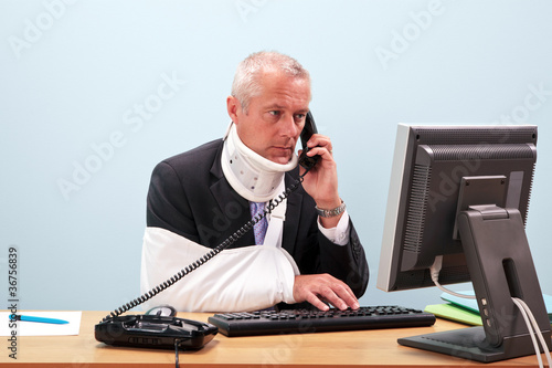 Injured businessman at his desk on the phone photo