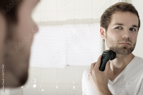 An attractive young man shaves