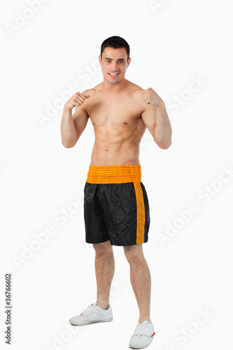Smiling young boxer with bare fists up