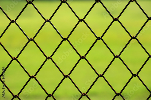 Closeup detail of chain link fence with green grass background