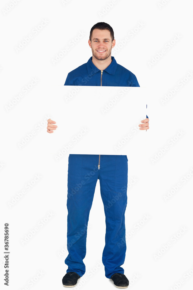 Smiling young mechanic in boiler suit holding a banner Smiling young mechanic in boiler suit holding a banner