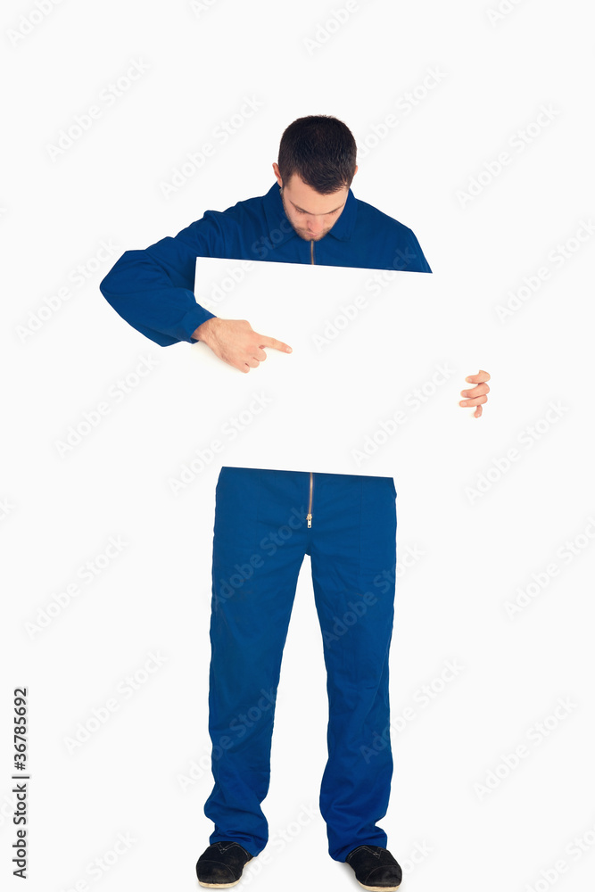 Young mechanic in boiler suit pointing on banner in his hands Young mechanic in boiler suit pointing on banner in his hands