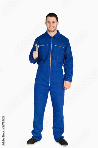 Smiling young mechanic in boiler suit with a wrench