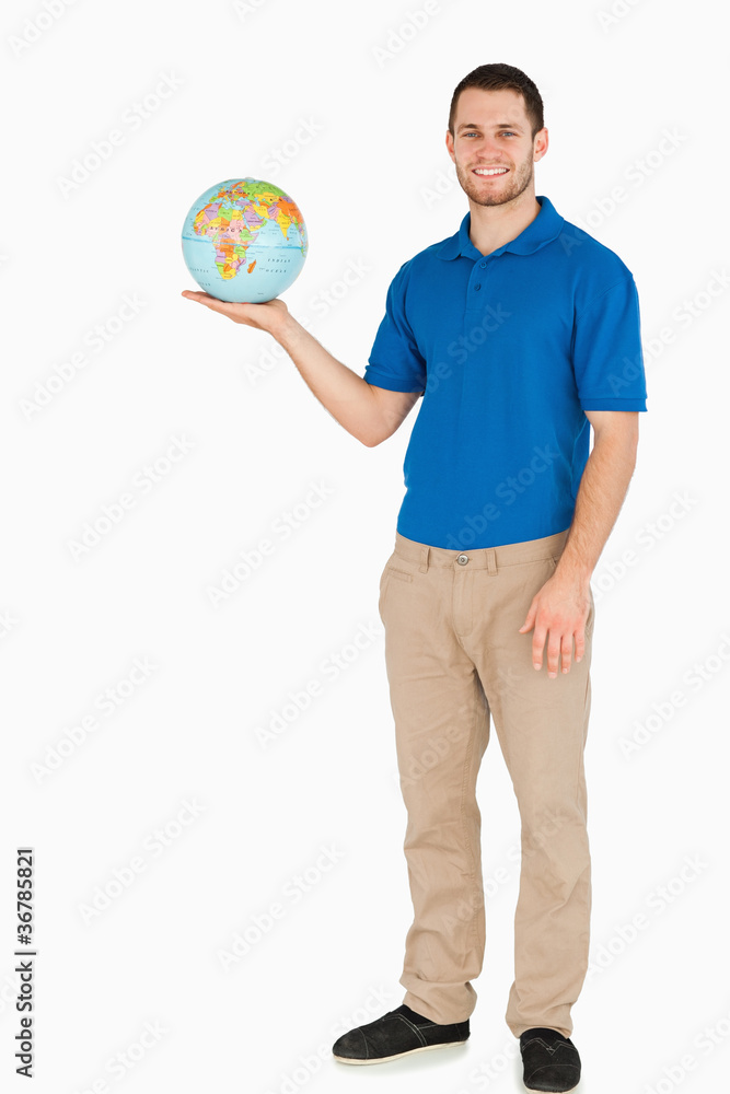 Fototapeta premium Smiling young salesman holding globe in his palm