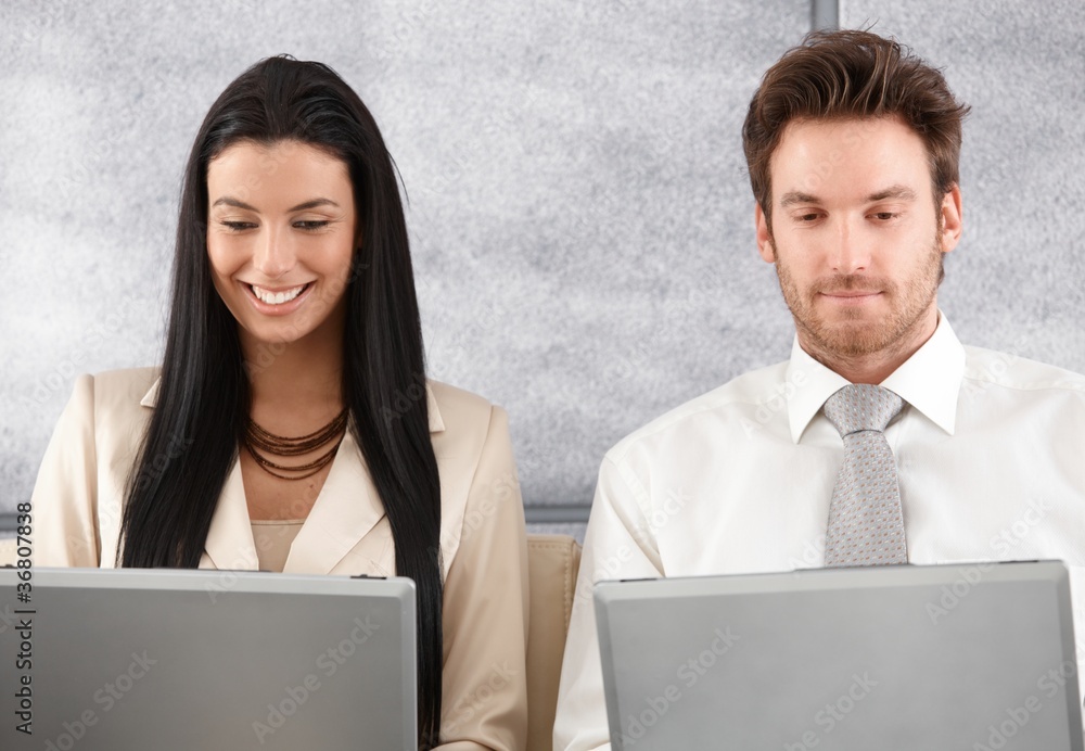 Young colleagues working on laptop smiling Young colleagues working on laptop smiling