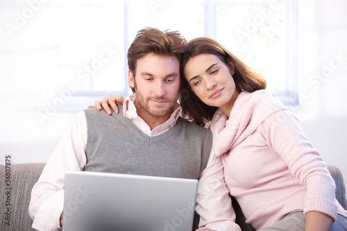 Young couple using laptop at home smiling