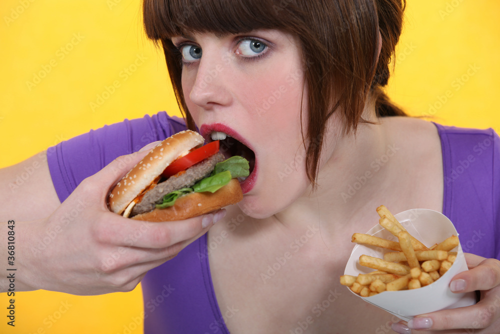 woman eating hamburger and French fries woman eating hamburger and French fries