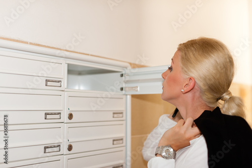 Frau sieht nach ihrer Post im Briefkasten photo