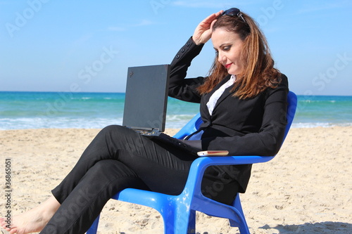 Business woman sits and works, near the ocean
