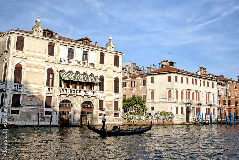 Gondola on golden waters of Grand Canal in Venice at sunset