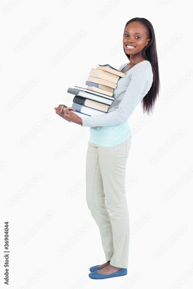 Side view of smiling young woman carrying a stack of books Side view of smiling young woman carrying a stack of books