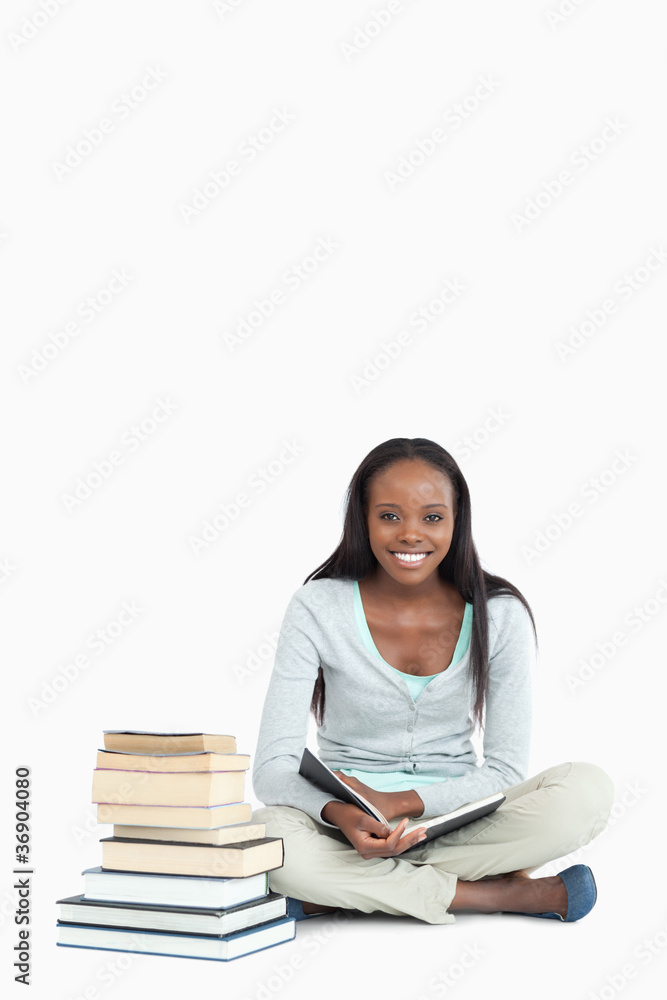 Smiling young woman sitting next to a pile of books Smiling young woman sitting next to a pile of books