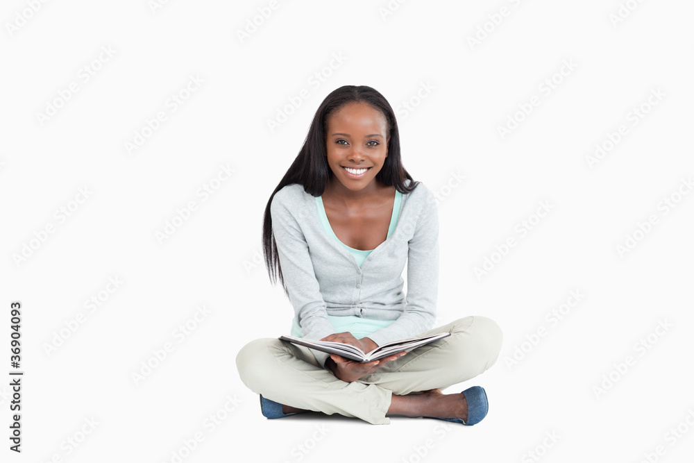 Smiling young woman sitting on the floor with a book Smiling young woman sitting on the floor with a book