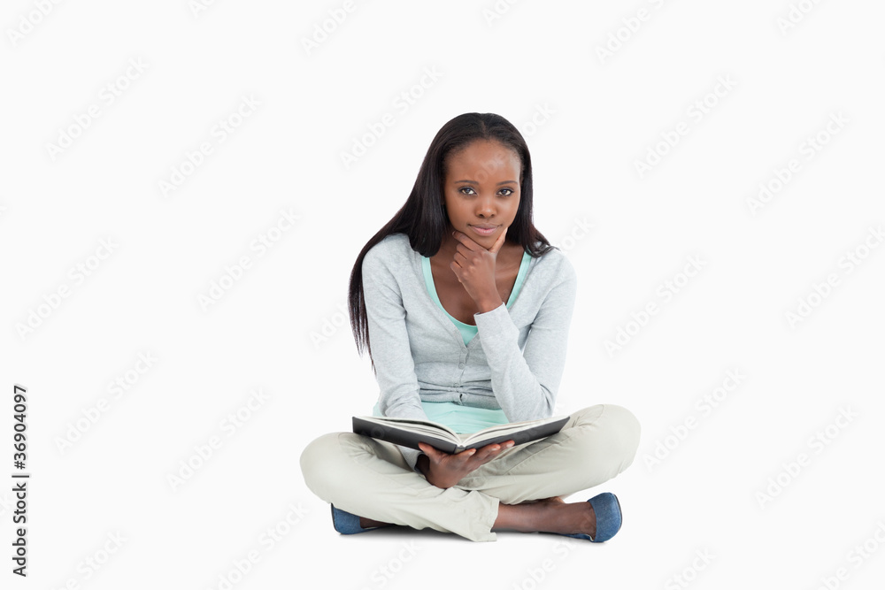 Young woman sitting on the floor thinking about her book Young woman sitting on the floor thinking about her book