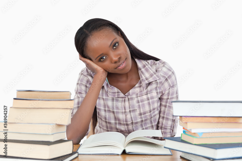 Young woman sitting on her desk with piles of books Young woman sitting on her desk with piles of books
