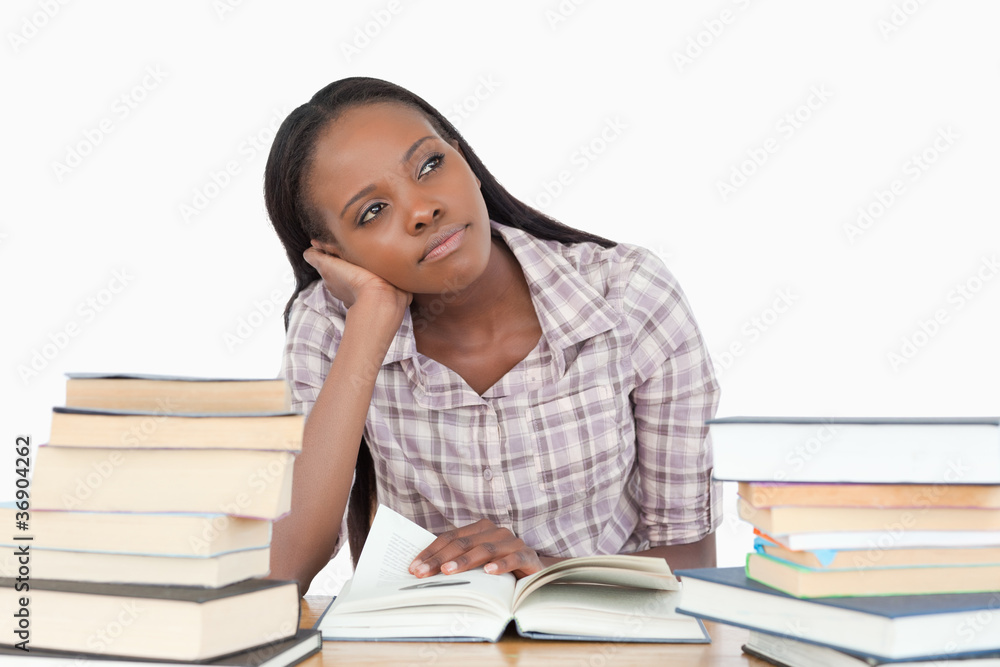 Young woman daydreaming next to stack of book Young woman daydreaming next to stack of book